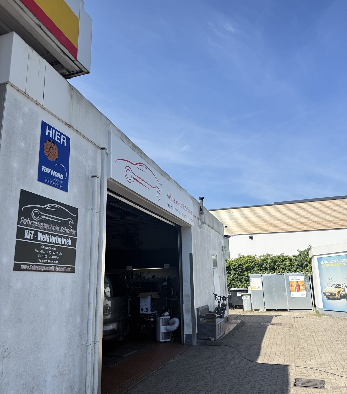 Die Werkstatt von außen, mit Schild und offenem Tor
